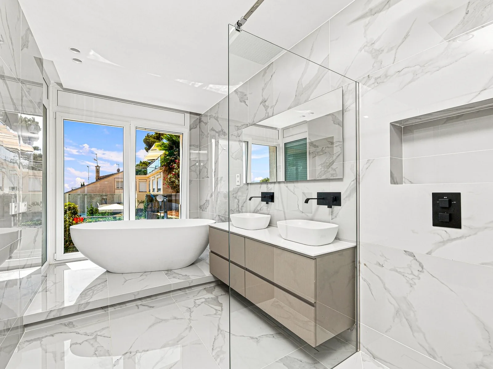 Baño principal de mármol con bañera exenta junto al ventanal, villa en Castelldefels