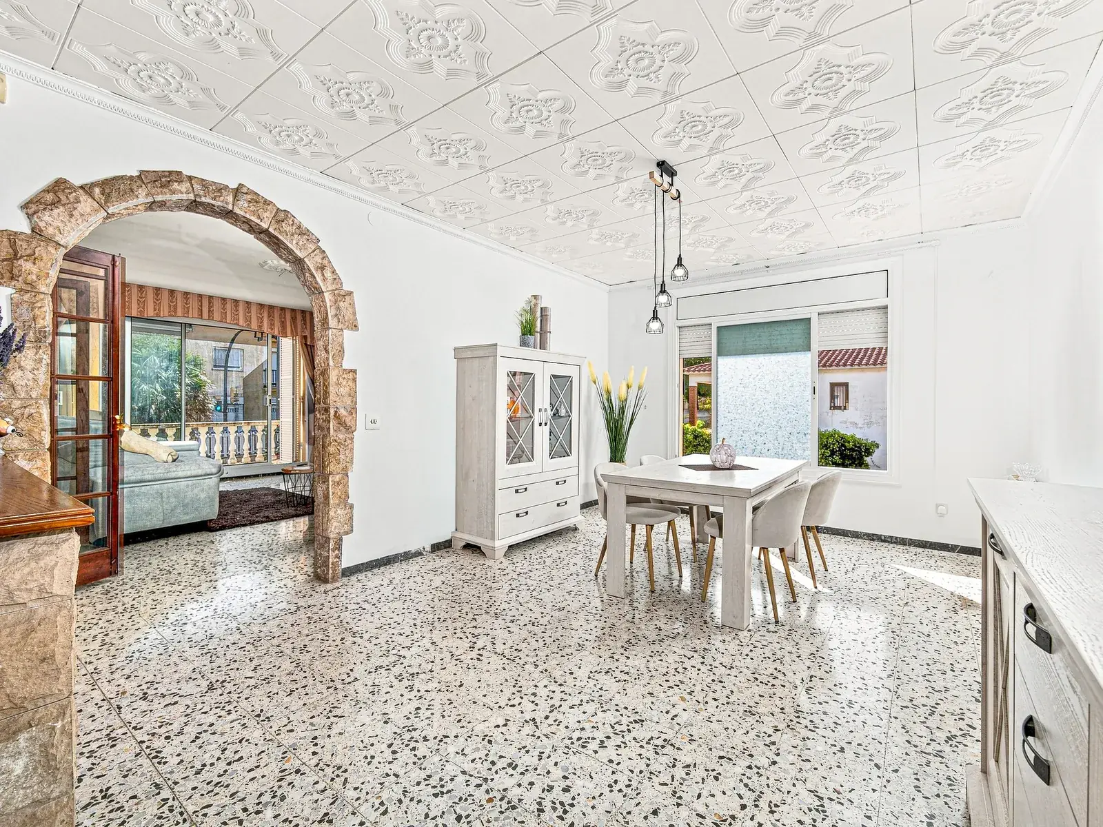 Comedor con arco de piedra y salida a la galería, fotografía inmobiliaria de Visoria