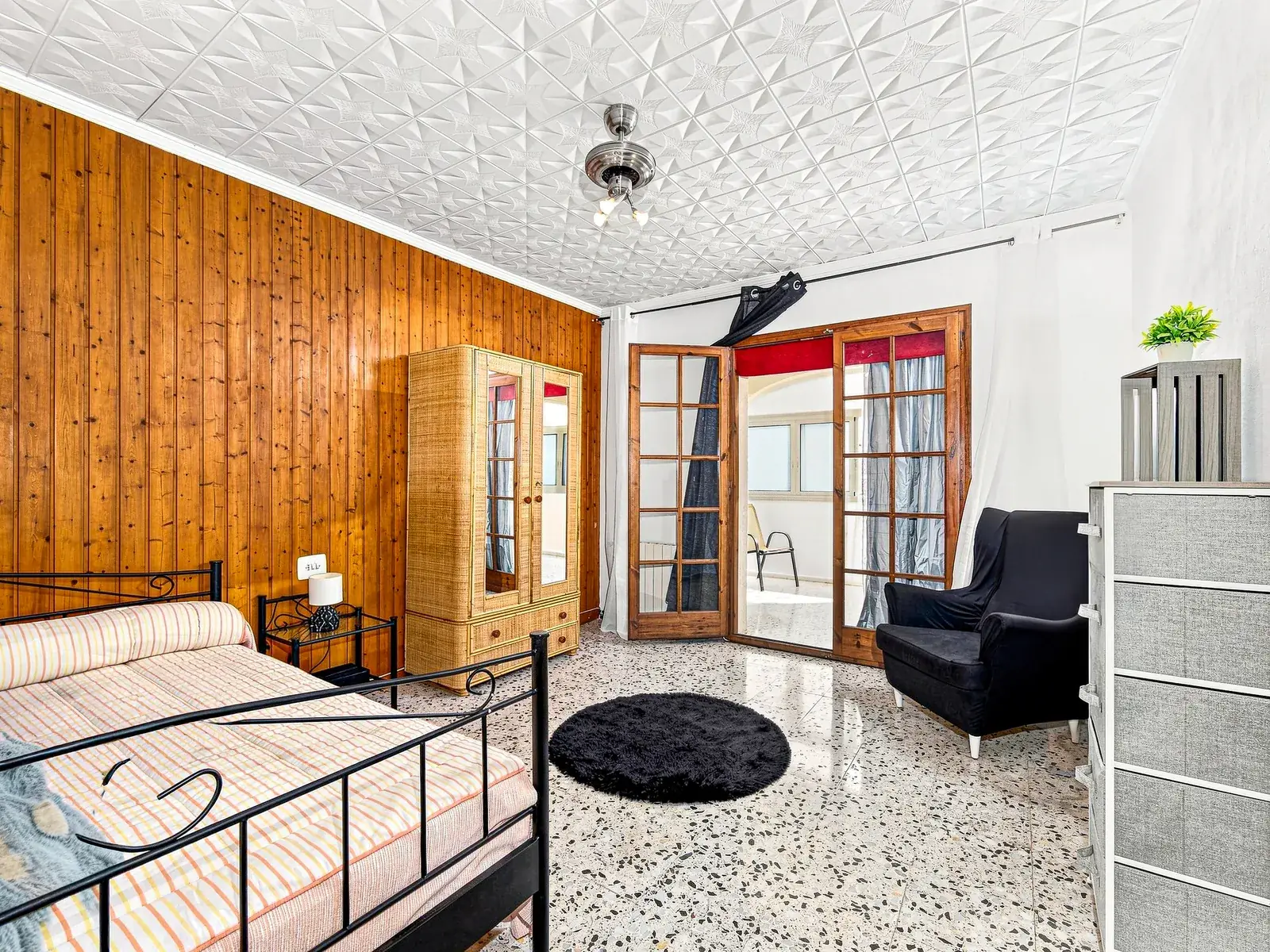 Dormitorio con pared de madera y salida a la galería