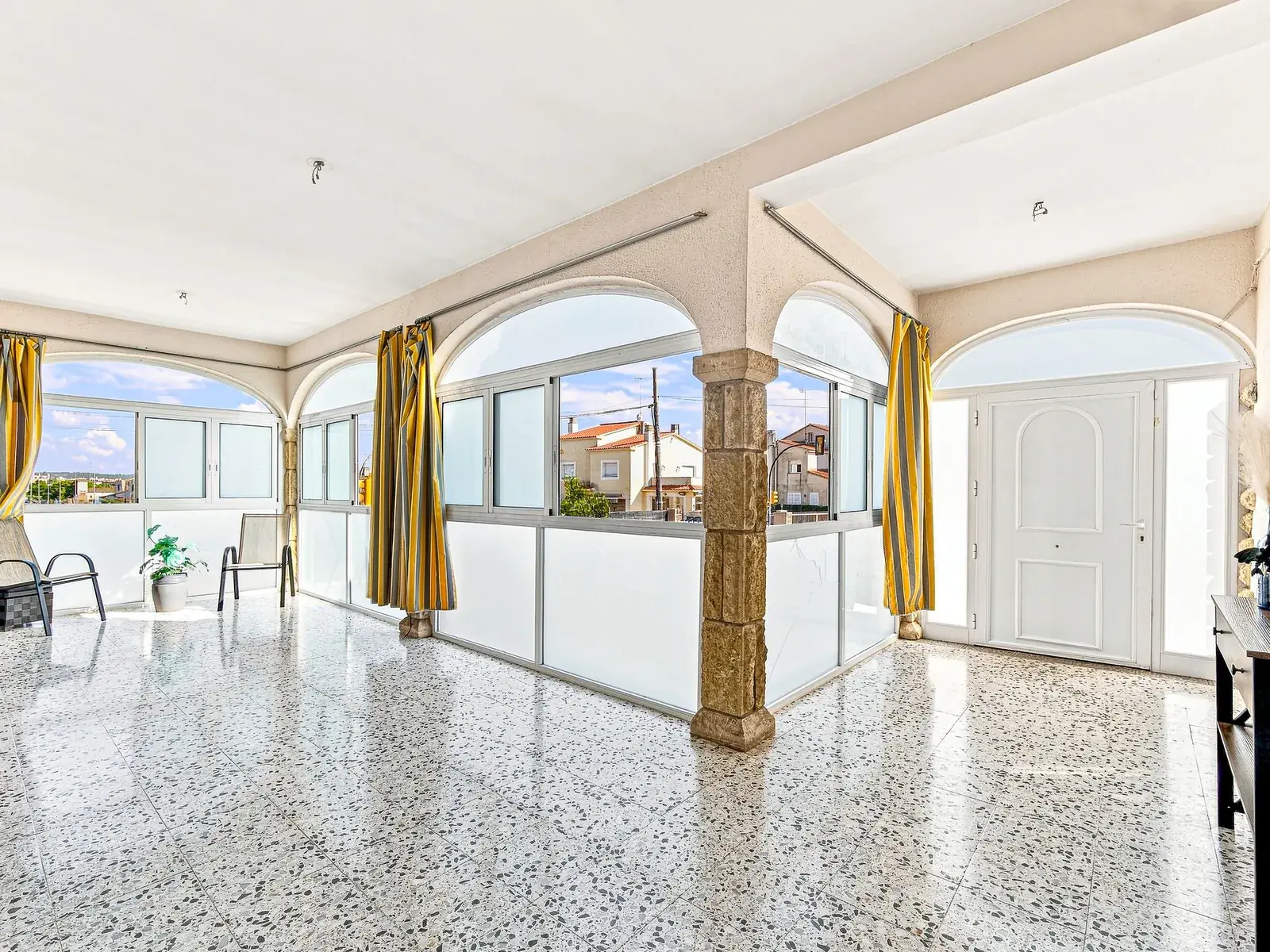 Galería acristalada con columnas y vistas al pueblo