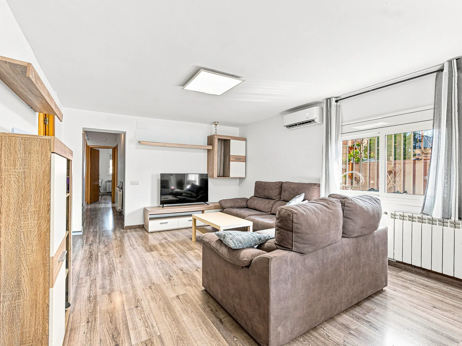 Salón con sofá rinconera y mueble de televisión, fotografía inmobiliaria de Visoria